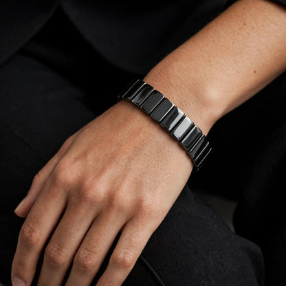 Black hematite tile bracelet worn on a wrist with a black blazer